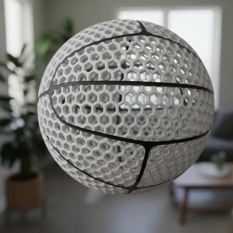 May include: A white basketball with a unique honeycomb design. The ball features black lines that outline the panels, creating a striking contrast. The intricate pattern gives the ball a modern, artistic look, suitable for display or play.