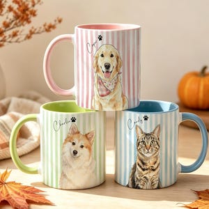Puede incluir: Tres tazas de cerámica con rayas verticales e ilustraciones personalizadas de mascotas. La taza superior es rosa con un golden retriever llamado Cooper. La taza inferior izquierda es verde claro con un perro llamado Charlie y la derecha es azul con un gato llamado Candy.