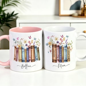 Op de afbeelding: Twee witte keramische mokken met een kleurrijke illustratie van een rij boeken met wilde bloemen en vlinders. De linker mok heeft een roze handvat en binnenkant met de naam Bettina, de rechter mok heeft de naam Mum eronder gedrukt.