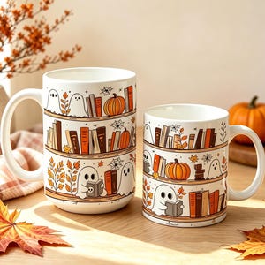 Puede incluir: Dos tazas de cerámica blanca con una ilustración repetida de estanterías de madera llenas de libros coloridos, calabazas naranjas, hojas de otoño, telarañas y pequeños fantasmas blancos, uno de los cuales está leyendo un libro.