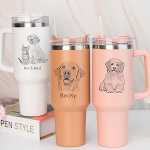 May include: Three stainless steel tumblers with handles and clear lids. The white tumbler features a cat and dog illustration with the text Rio & Med. The tan tumbler shows a dog portrait with the name Becky. The pink tumbler displays a dog illustration.