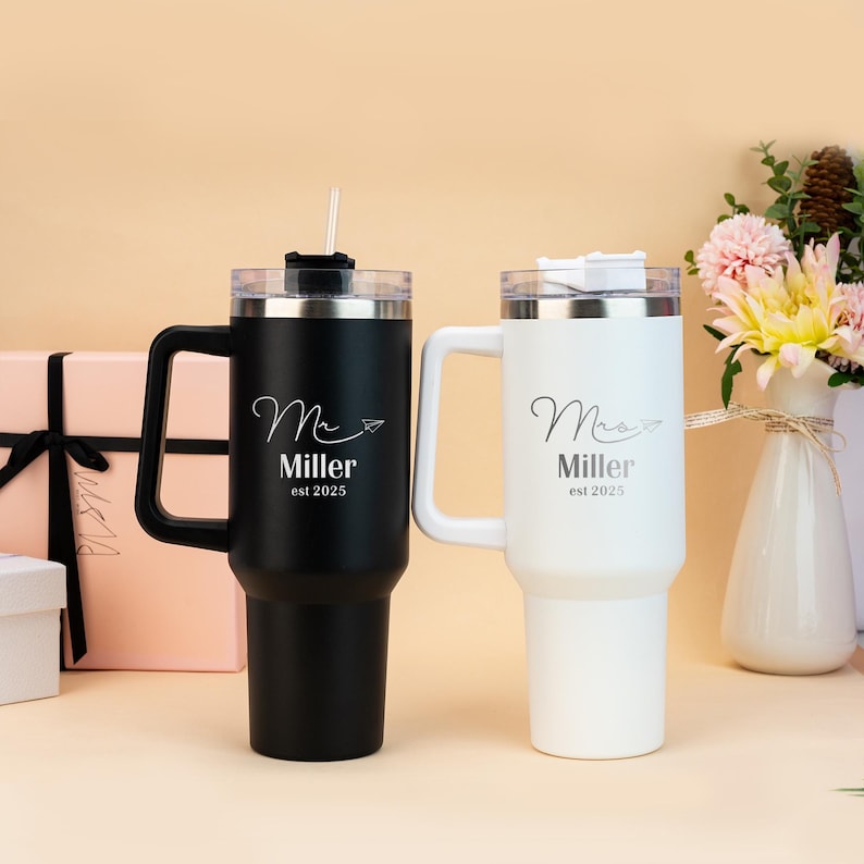 Pu&ograve; includere: Due tazze da viaggio in acciaio inossidabile con manici e coperchi. La tazza nera dice "Mr. Miller est 2025" e la tazza bianca dice "Mrs. Miller est 2025".