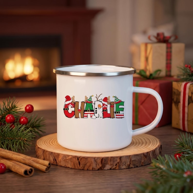 K&ouml;nnte beinhalten: Ein wei&szlig;er Emaillebecher mit silbernem Rand, der den Namen CHARLIE in gro&szlig;en, bunten Buchstaben zeigt. Jeder Buchstabe ist mit weihnachtlichen Elementen wie Weihnachtsmannm&uuml;tzen, Rentiergeweihen und Streifenmustern verziert.