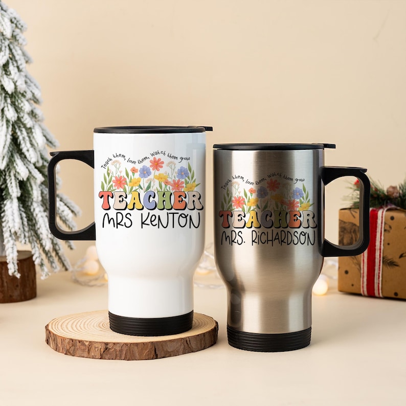 May include: Two travel mugs with black handles and lids. One is white with a floral design and the text "TEACHER MRS. KENTON". The other is silver with the text "TEACHER MRS. RICHARDSON". Both mugs have the quote "Teach them, love them, watch them grow".