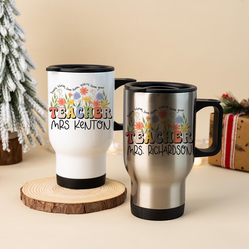 May include: Two travel mugs with black lids and handles. One is white, the other is silver. Both mugs have the word "TEACHER" in colorful retro lettering, with a floral design and a teacher's name.