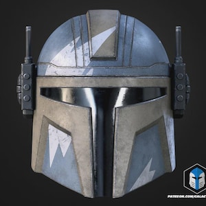 May include: A Mandalorian helmet with a weathered, battle-worn appearance. The helmet features a blue and tan color scheme with white chevron markings. It has a visor and two antenna-like structures on the sides. The bottom right corner has a logo and website address.