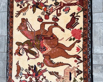 Puede incluir: Alfombra rectangular beige con un patrón detallado que presenta caballos marrones, pájaros y elementos florales. La alfombra tiene un borde marrón oscuro con diseños intrincados y un borde con flecos. El diseño central muestra una escena dinámica con animales y árboles.
