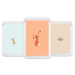 Puede incluir: Tres fundas para teléfono con ilustraciones de animales. La primera funda es azul claro con una jirafa. La segunda funda es melocotón con un zorro mirando hacia arriba a las hojas que caen. La tercera funda es beige con un perezoso en una rama.