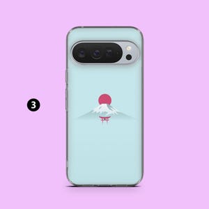 May include: A clear phone case with a light blue background featuring a minimalist design of a red sun, a snow-capped mountain, and a red torii gate. The phone case has a camera cutout and side buttons.