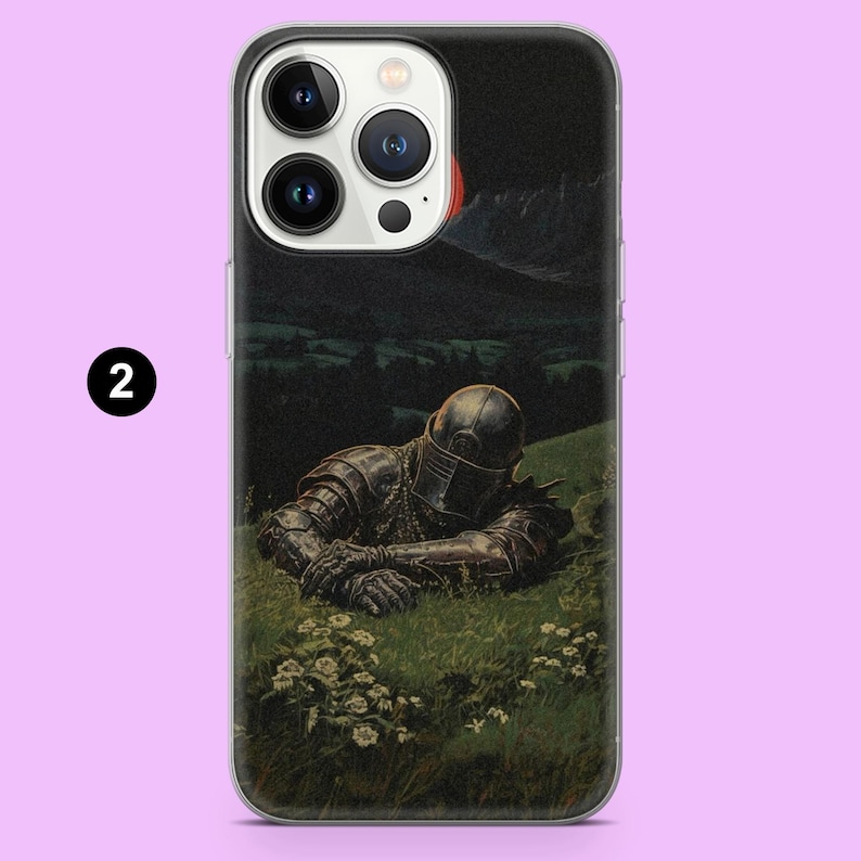 May include: A phone case featuring a painting of a knight in full armor resting in a grassy field. The artwork has a dark, dramatic tone with a night sky and distant mountains. The case is clear with a black number 2 in the corner.