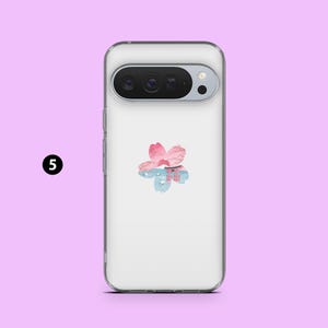 May include: Transparent phone case with a floral design. The design features a pink and blue flower with a Japanese-style building in the centre. The case is shown against a light purple background.