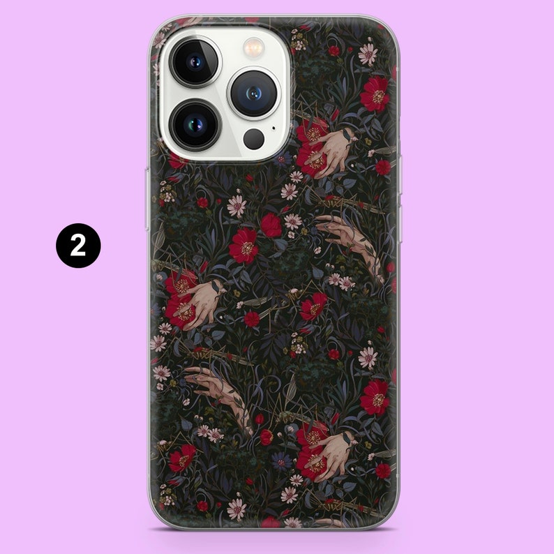 May include: A clear phone case with a dark floral design of red flowers, white daisies, and stylized hands. The case has a transparent border and a camera cutout. The number "2" is in a white circle in the upper left corner.