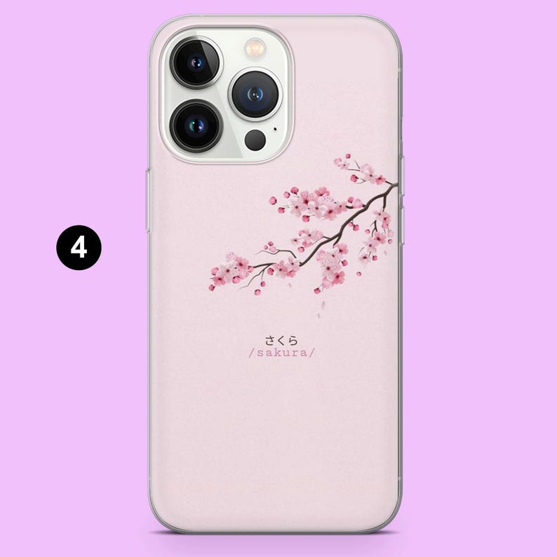 Pode incluir: Capa de telem&oacute;vel rosa claro com um ramo de flores de cerejeira rosa. A palavra japonesa "sakura" e a sua romaniza&ccedil;&atilde;o est&atilde;o impressas abaixo do desenho floral. A capa tem uma borda transparente e um recorte para a c&acirc;mara.