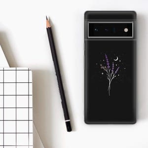 May include: Black phone case featuring a floral design with lavender and a crescent moon. The case is next to a black pencil and a white notebook with a grid pattern. The phone case has a camera and flash.