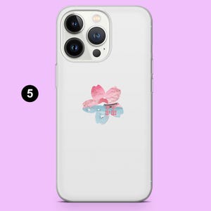 Pode incluir: Uma capa transparente para iPhone com um design floral rosa e azul e texto japon&ecirc;s. O design inclui uma flor rosa com uma cena de montanha e &aacute;gua azul. A capa tem um recorte para a c&acirc;mera e o n&uacute;mero 5 em um c&iacute;rculo preto.