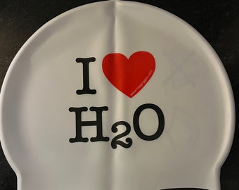 May include: White silicone swim cap with black text that reads "I love H2O" and a red heart with the website "www.tagoggles.com" printed on it.