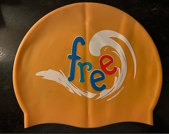 May include: Orange silicone swim cap with a white wave design and the word "free" in colorful letters. The text "www.laggoggles.com" is printed on the bottom.