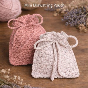 Può includere: Due sacchetti all'uncinetto rosa e bianco sporco, con chiusure a coulisse. Il testo "Crochet Sachet Pouch" e "Mini Drawstring Pouch" sono visibili. Il testo "PDF Crochet Pattern" è anch'esso visibile.