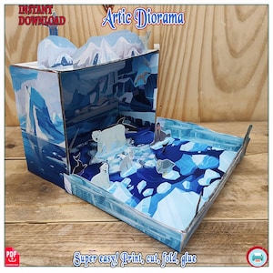 Puede incluir: Un diorama ártico emergente con osos polares, focas e icebergs. La escena está ambientada en una caja con ilustraciones azules y blancas. El texto de la imagen dice "Artic Diorama" y "Super easy! Print, cut, fold, glue."