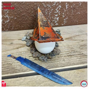 May include: A papercraft model featuring a rusty orange pyramid structure atop a white sphere, surrounded by small rocks. A blue and brown paper sword lies in the foreground. The words "Instant Download" are visible in the upper left corner.