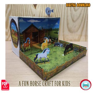 Op de afbeelding: Een papieren knutseldiorama met een geprinte boerderijscène met een windmolen, groene weide en verschillende paardenfiguren. De structuur bevat een zijpaneel met een hoefijzerframe en de tekst DIGITAL DOWNLOAD in de rechterbovenhoek.