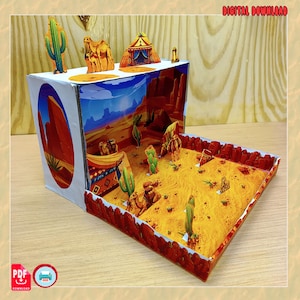 Può includere: Una scatola diorama a tema deserto con un paesaggio stampato che include cammelli, cactus e tende. L'interno mostra un terreno sabbioso con formazioni rocciose rosse, mentre l'esterno presenta scene desertiche. Il testo recita DIGITAL DOWNLOAD.