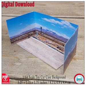 以下が含まれることがあります： 1/64スケールの玩具車ケースの背景。砂漠の道と山脈が青い空と雲の下に描かれています。ケースのサイズは8.3 x 4.4 x 4.4 cmです。「Digital Download」の文字が上部にあります。