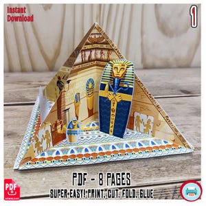 May include: A papercraft Egyptian pyramid with a blue and gold sarcophagus and hieroglyphic details. The pyramid is open, revealing interior walls with ancient Egyptian art. Text includes "Instant Download" and "PDF - 8 PAGES".