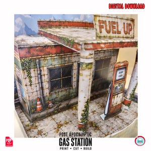May include: A papercraft model of a weathered gas station featuring a roof sign that reads FUEL UP. The structure displays rust, grime, and vine details, with a fuel pump, a traffic cone, and windows. Text at the bottom reads POST APOCALYPTIC GAS STATION.