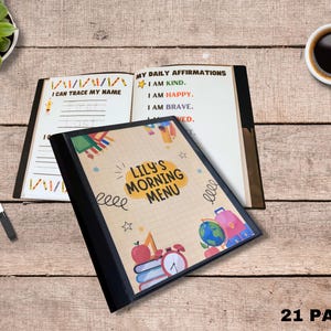 May include: A children's activity book with a black cover featuring the text "Lily's Morning Menu" and colorful illustrations. The open pages display tracing exercises and affirmations. A cup of coffee and markers are also visible.