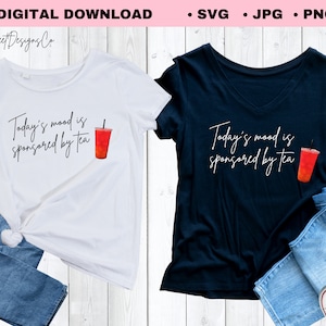 May include: Two t-shirts, one white and one navy blue, with the text "Today's mood is sponsored by tea" and a watercolor illustration of a red drink. The white t-shirt is paired with blue jeans, and the navy blue t-shirt is paired with blue jeans and white sneakers.