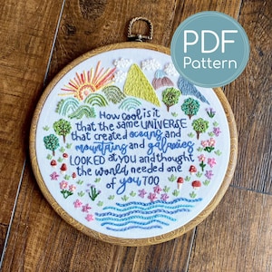 May include: Embroidered hoop art with a nature-themed design. The artwork features a sun, mountains, trees, and water, with the text "How cool is it that the same UNIVERSE that created oceans and mountains and galaxies LOOKED at you and thought the world needed one of you TOO."