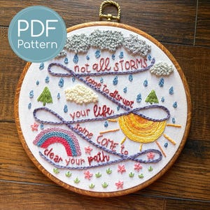 May include: Embroidered hoop art with the text "not all STORMS come to disrupt your life, some come to clear your path." The design includes a rainbow, sun, clouds, rain, and flowers. The hoop is 8 inches in diameter.