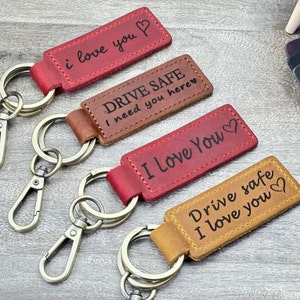 May include: Four leather keychains with metal rings. The keychains have different colors and messages: red with "i love you", brown with "DRIVE SAFE I need you here", red with "I Love You", and brown with "Drive safe I love you".