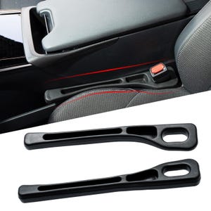 May include: Black car seat belt extenders with a curved design and an oval opening at the end. The extenders are shown in the car's interior, next to the seat belt buckle.