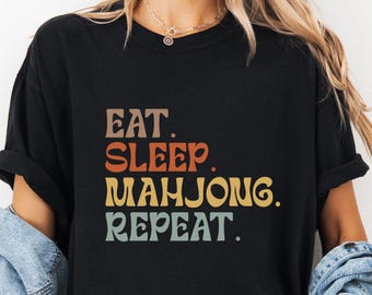 May include: Black t-shirt with a retro-style graphic that reads "Eat. Sleep. Mahjong. Repeat."