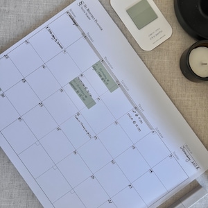 May include: A white monthly planner with a calendar grid for January 2024. The planner has a section for each day of the week, with space for writing appointments and notes. There are several sticky notes with handwritten text on the calendar.