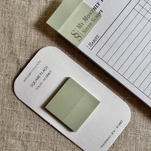 Op de afbeelding: Een pak vierkante plakbriefjes in een lichtgroene kleur. Het pak is gelabeld "Square Flags Vol. 01 - Le Début" en "Transparent 3CM - 30 Sheet".