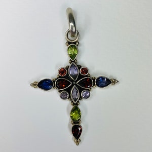 Peut inclure: Un pendentif en argent en forme de croix avec un motif floral orn&eacute; de pierres pr&eacute;cieuses vari&eacute;es, dont de l'am&eacute;thyste, du grenat, du p&eacute;ridot et du saphir.