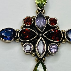 Peut inclure: Un pendentif en forme de croix en argent avec une vari&eacute;t&eacute; de pierres pr&eacute;cieuses, dont de l'am&eacute;thyste, du p&eacute;ridot et du grenat.