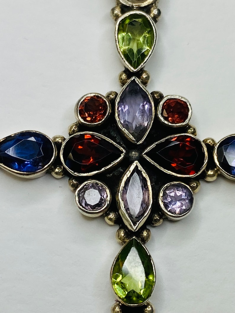 Peut inclure: Un pendentif en forme de croix en argent avec une vari&eacute;t&eacute; de pierres pr&eacute;cieuses, dont de l'am&eacute;thyste, du p&eacute;ridot et du grenat.