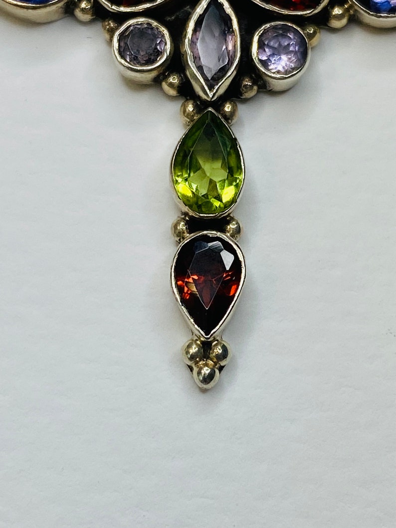 Peut inclure: Un pendentif en argent avec un groupe de pierres pr&eacute;cieuses violettes et une rang&eacute;e de pierres pr&eacute;cieuses vertes, rouges et violettes.