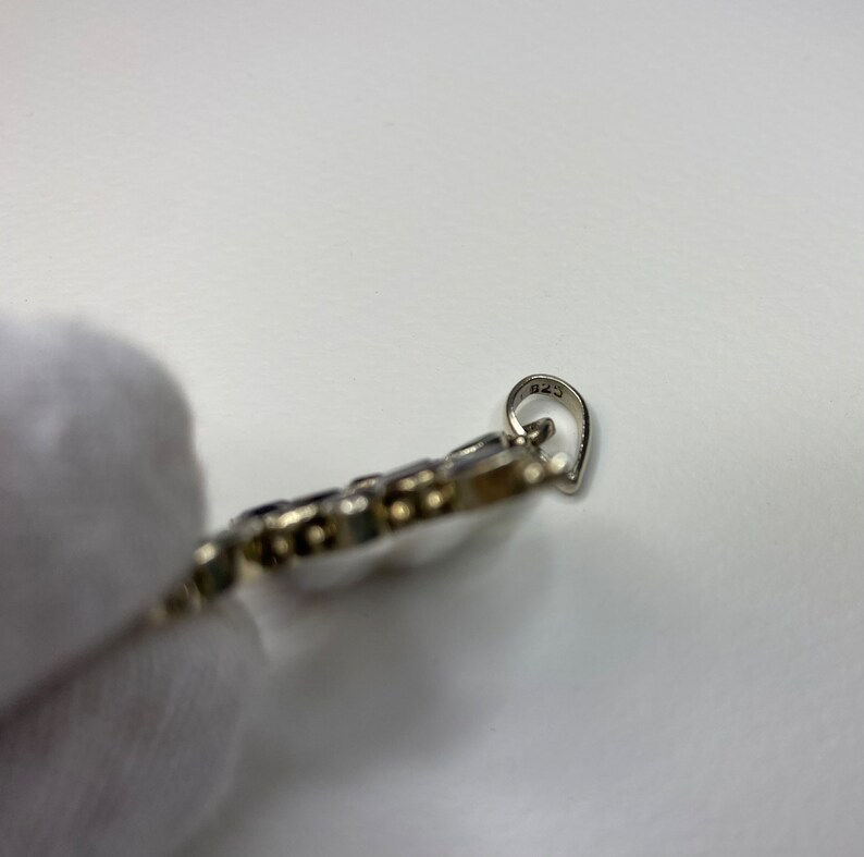 Peut inclure: Pendentif en argent avec une b&eacute;li&egrave;re en forme de c&oelig;ur. Le pendentif est d&eacute;cor&eacute; de petites pierres rondes. Le dos du pendentif est marqu&eacute; du num&eacute;ro "925".