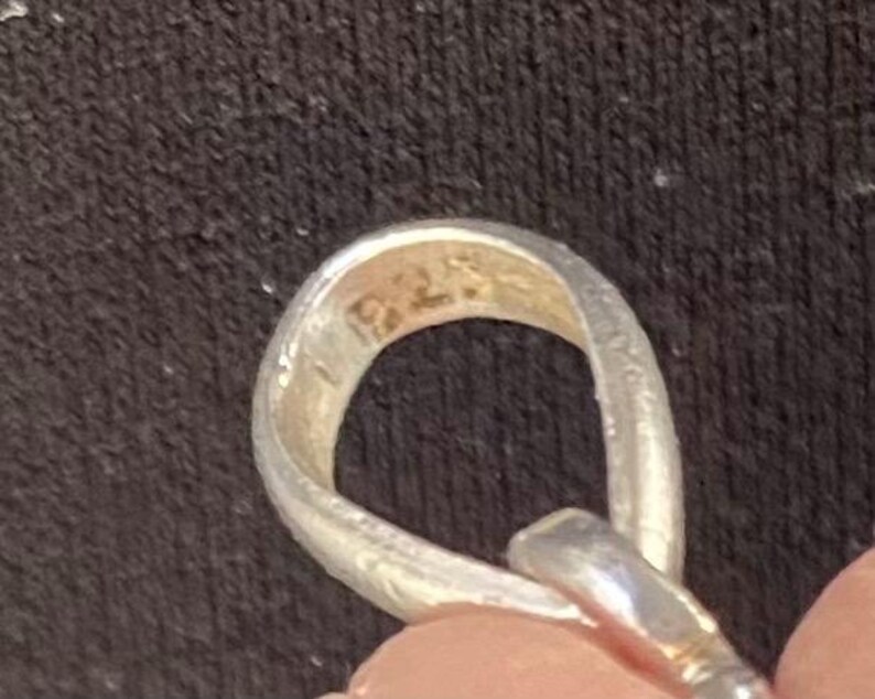 Peut inclure: Gros plan d'un pendentif en argent avec une boucle en haut. Le pendentif porte l'inscription "92.5" &agrave; l'int&eacute;rieur.