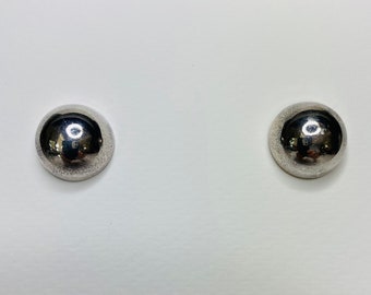 Op de afbeelding: Een paar zilveren oorbel studs met een rond, glad en reflecterend oppervlak.