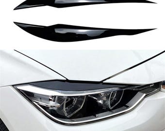 May include: A pair of black headlight covers for a car. The covers are made of a durable, flexible material and are designed to protect the headlights from damage.
