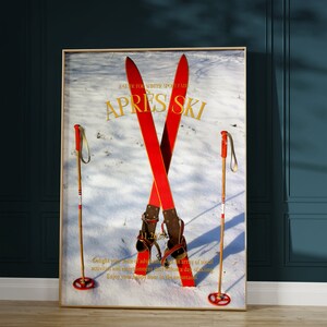 K&ouml;nnte beinhalten: Ein Vintage-Poster mit dem Text "A Guide to Winter Sport Fairs APRES SKI" in goldenen Buchstaben. Das Poster zeigt ein Paar rote Ski, die &uuml;bereinander gekreuzt sind, mit Skist&ouml;cken auf beiden Seiten. Der Hintergrund ist eine Schneelandschaft.