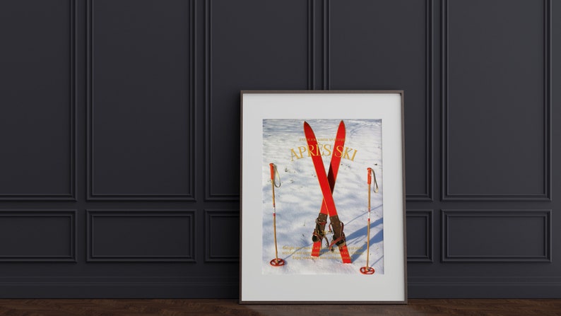 K&ouml;nnte beinhalten: Ein gerahmtes Poster mit einer Vintage-Skiszene. Das Poster zeigt zwei rote Ski, die im Schnee gekreuzt sind, mit Skist&ouml;cken auf beiden Seiten. Der Text "Apr&egrave;s Ski" ist in goldenen Lettern auf dem Poster gedruckt.