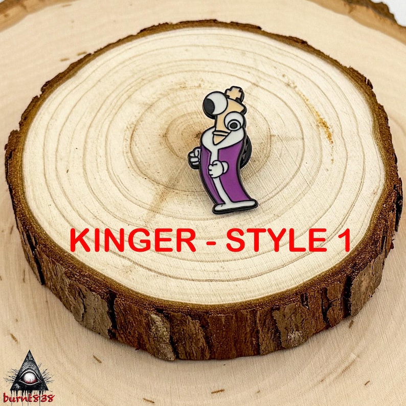Puede incluir: Un pin de esmalte colorido con un personaje de dibujos animados con ojos grandes, vistiendo una t&uacute;nica morada con ribetes blancos. El pin est&aacute; etiquetado como "Kinger - Style 1" en texto rojo. El pin est&aacute; sobre una rodaja de madera.