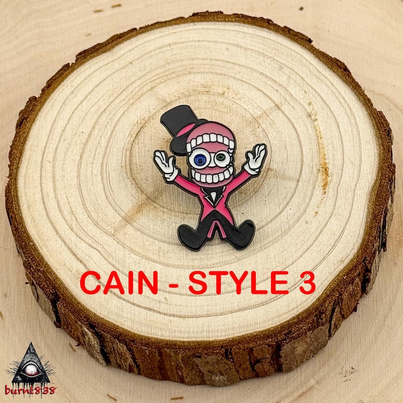 Puede incluir: Un pin de dibujos animados con un personaje con un traje rosa, sombrero de copa negro y boca abierta con dientes. El pin tiene el texto "CAIN - STYLE 3" en rojo. El pin est&aacute; sobre una rodaja de madera.